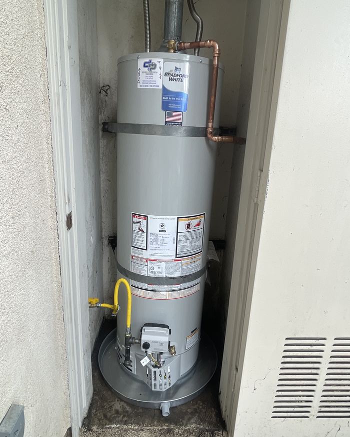 New 50-gallon gas water heater installed in an exterior closet with seismic strapping