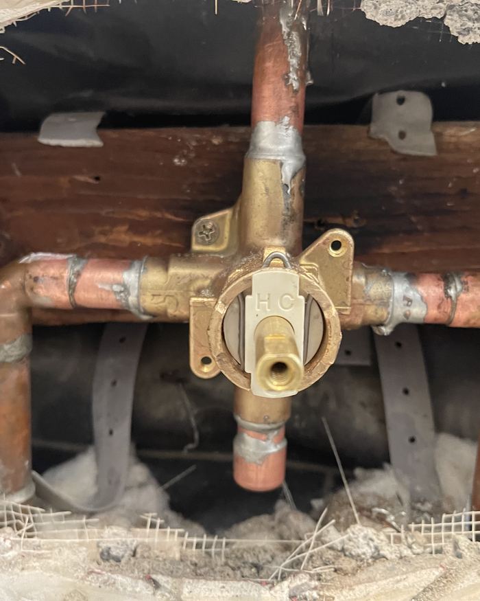 New shower valve body soldered into copper lines inside a tiled wall