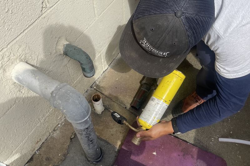 Plumber clearing a sewer cleanout with a drain machine in the South Bay