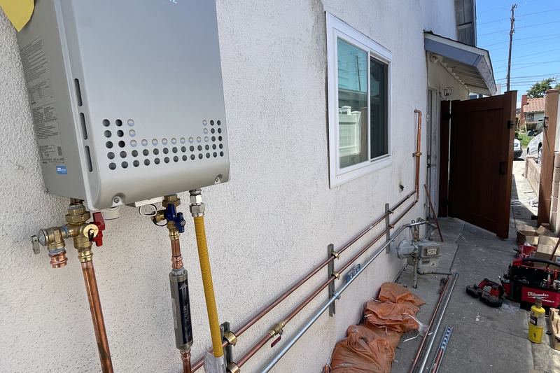 Noritz tankless water heater installed on an exterior wall with new copper and gas lines