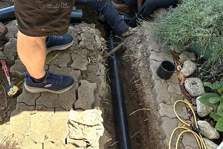 New ABS sewer line being laid in an open trench beside a Torrance walkway